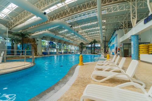 una gran piscina con sillas blancas en un edificio en Sono Moon Danyang, en Danyang