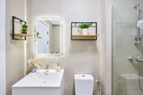 een badkamer met een wastafel, een toilet en een spiegel bij AdeMar Luxury Apartment- Spa&Pool Beach Resort in Mamaia