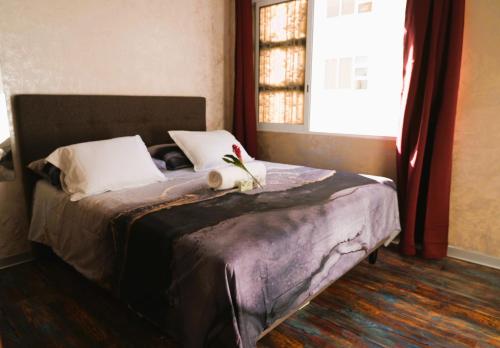 Papeete appartement entier à 10 min de L'aéroport في بابيت: غرفة نوم عليها سرير مع وردة