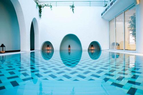 a swimming pool with blue water in a building at Aegialis Hotel & Spa in Aegiali