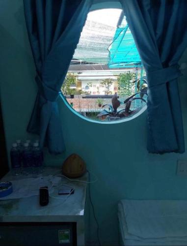 a room with a window with blue curtains and a table at Phuoc Long Homestay in Ha Tien