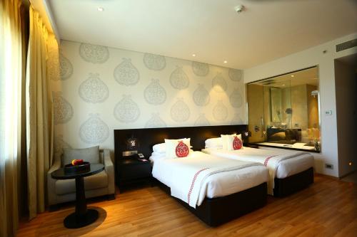 a hotel room with two beds and a mirror at Vivanta Guwahati in Guwahati