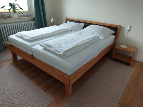 Una cama con sábanas blancas y almohadas. en Ferienwohnung Lojane, en Kranenburg