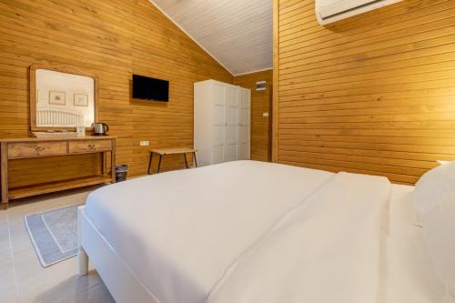 a bedroom with a white bed and a wooden wall at TurkuazKöy in Finike