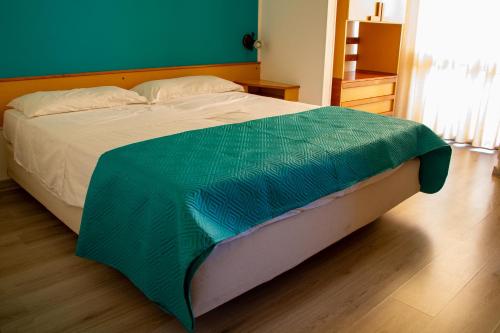 a bed with a green blanket on top of it at Hotel Colibrì in Alessano