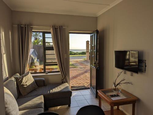 uma sala de estar com um sofá e uma televisão em @Kitchens em Jeffreys Bay