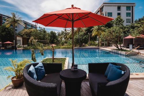 a table with an umbrella next to a swimming pool at Amari Hua Hin in Hua Hin
