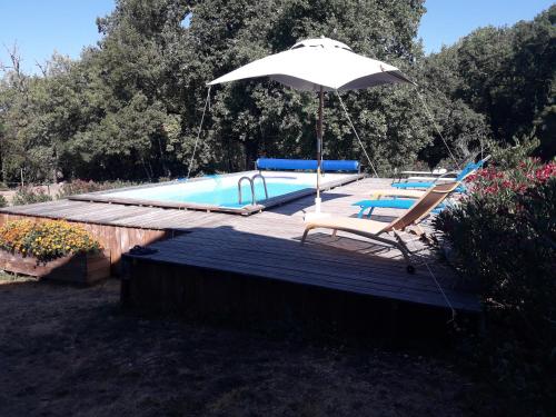 une piscine avec un parasol et deux chaises dans l'établissement gîtes de Combelcau, le Pigeonnier, à Flaugnac