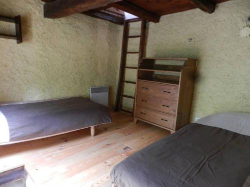 une chambre avec deux lits et une échelle et une commode dans l'établissement gîtes de Combelcau, le Pigeonnier, à Flaugnac
