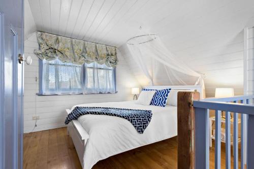 a white bedroom with a bed and a window at Murray River Spa Retreat in Echuca