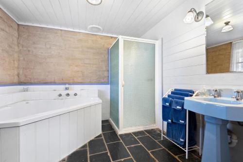 a bathroom with a tub and a sink and a shower at Murray River Spa Retreat in Echuca