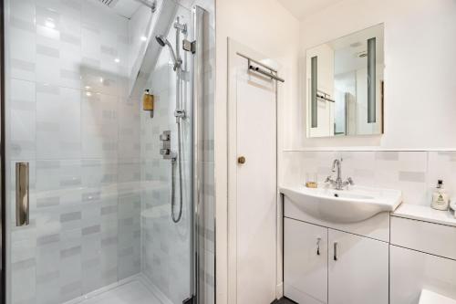 uma casa de banho branca com um lavatório e um chuveiro em Urquhart Bay Croft em Drumnadrochit