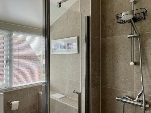 een douche met een glazen deur in de badkamer bij Hello Zeeland - Vakantiehuis Zwin 182 in Breskens