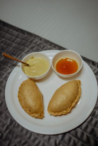a plate with two pancakes and two bowls of dipping sauce at Apple Blush Retreat - Tirthan Valley in Gushaini