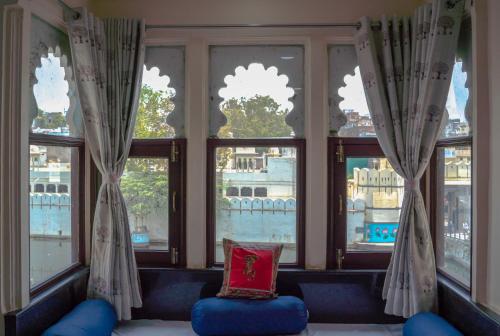 Zimmer mit einem Fenster mit einem blauen Stuhl und einem Kissen in der Unterkunft Hide-In Udaipur - A Lake View Boutique Hotel in Udaipur