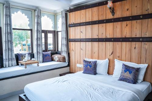 two beds in a room with wooden walls and windows at Hide-In Udaipur - A Lake View Boutique Hotel in Udaipur