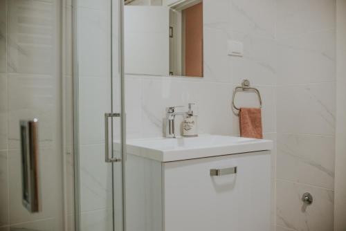 een witte badkamer met een wastafel en een douche bij David 3 in Ruma