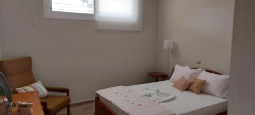 a bedroom with a bed and a chair and a window at Aqua in Artemida