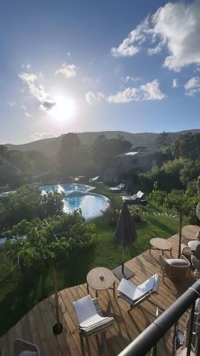 a deck with chairs and an umbrella and a pool at Hôtel Ambassador Palombaggia in Porto-Vecchio