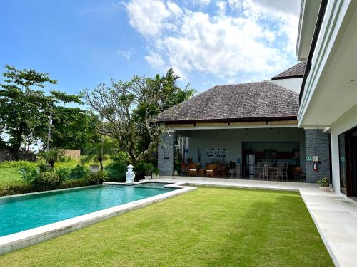 a backyard with a swimming pool and a house at Oshan Villas Bali in Canggu