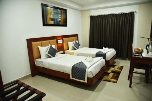two beds in a hotel room with a desk at The Altruist Business Stays- New Town, Kolkata in Kolkata