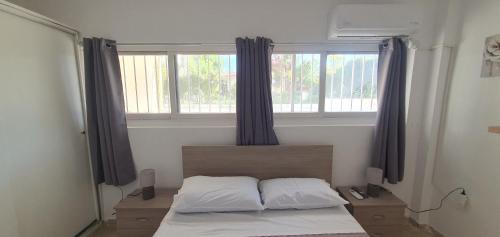 Schlafzimmer mit einem Bett und einem Fenster mit Vorhängen in der Unterkunft TSAGGA HOUSE in Oropos