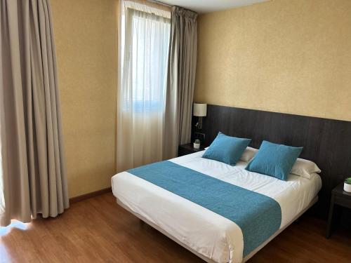 a bedroom with a large bed with blue pillows at Hotel 1948 Manresa in Manresa