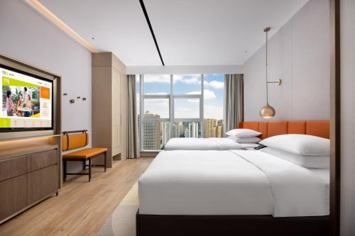 Home2 Suites By Hilton Wuhan Xudong في ووهان: غرفة فندقية بسريرين وتلفزيون بشاشة مسطحة