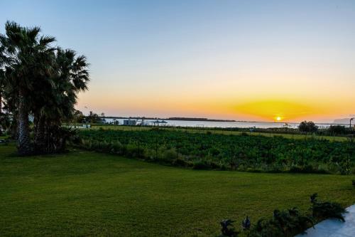 a sunset over the ocean and a field of crops at Casa B, Room 5 - mit Pool - at Lagoon - Lo Stagnone Kite Spot - Palm Kite Paradise in Marsala