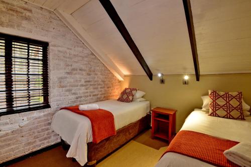 a bedroom with two beds and a brick wall at Dunkeld Country & Equestrian Estate in Dullstroom