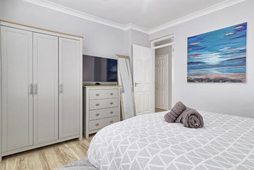 Modern Spacious 2 Bedroom Apartment in Brentwood في Shenfield: غرفة نوم بيضاء مع سرير وتلفزيون