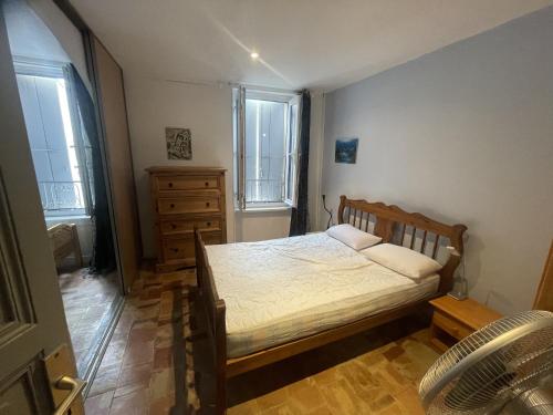 une chambre avec un lit et une commode et deux fenêtres dans l'établissement Chemin Neuf, à Peyriac-de-Mer