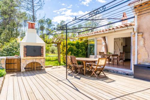 a wooden deck with a table and a fireplace at Albizia - Maison avec Piscine Privative in Draguignan