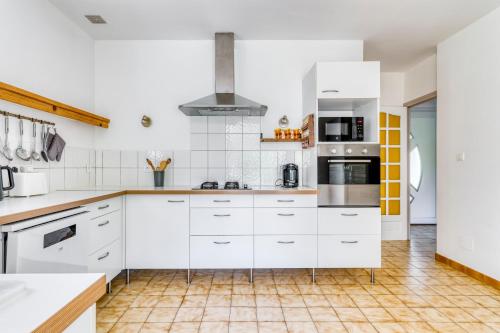 a kitchen with white cabinets and a tiled floor at Albizia - Maison avec Piscine Privative in Draguignan