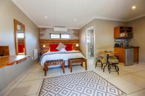 a bedroom with a large bed with red pillows at Touching Senses Garden Cottages in Bloemfontein