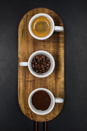 three cups of coffee on a wooden tray with coffee beans at Auberge du Lyonnais in Annecy
