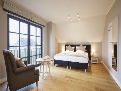 une chambre avec un lit, une chaise et une table dans l'établissement Reetland am Meer - Premium Reetdachvilla mit 3 Schlafzimmern, Sauna und Kamin F09, à Dranske