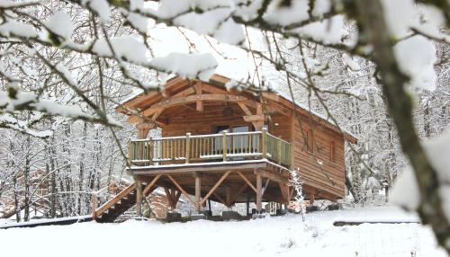 une cabane en rondins avec une terrasse dans la neige dans l'établissement Domaine de Ribeaugoutte, à Saint-Nabord