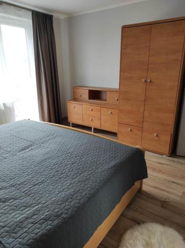 una camera con letto e cassettiera in legno di Apartamentai G&G a Jurbarkas