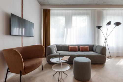 ein Wohnzimmer mit einem Sofa und 2 Stühlen in der Unterkunft Alpenblick Bern - kind of a hotel in Bern