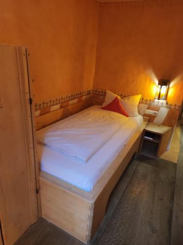 a bed in a small room with a white bedvisor at Hotel San Gabriele in Rosenheim