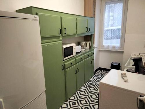 une cuisine avec des armoires vertes et un réfrigérateur blanc dans l'établissement Le nid douillet Vintage, à La Bourboule