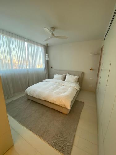 1 dormitorio con cama blanca y ventana en best sea view boutique two bedrooms, en Herzelia 