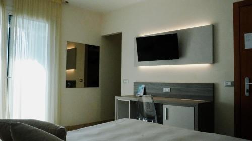 a hotel room with a bed and a television on the wall at Hotel Kaly in Ventimiglia