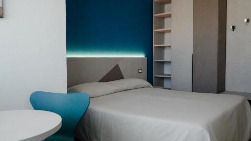 a bedroom with a bed and a blue chair at Hotel Kaly in Ventimiglia