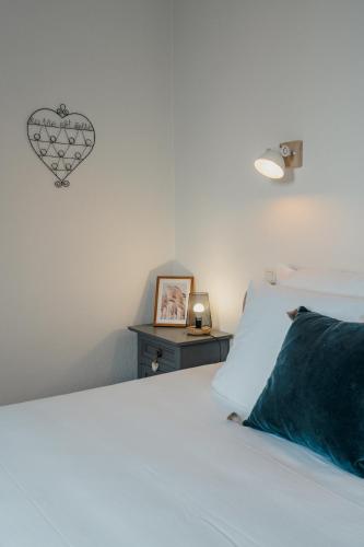 a white bed with a blue pillow and a heart on the wall at Hôtel l'Abbaye in Saint-Cyprien