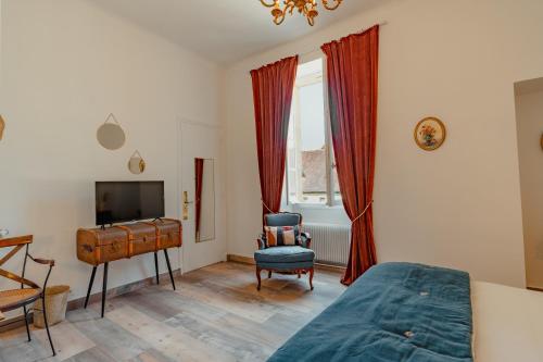a bedroom with a bed and a desk and a television at Hôtel l'Abbaye in Saint-Cyprien