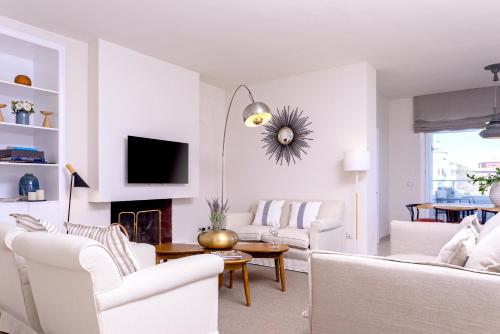 a living room with white furniture and a tv at Genteel Home Flamencos Terrace in Marbella