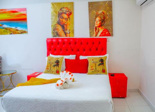 a bed with a red headboard and two paintings at Eagles Nest Self-Catering Apartments in Gaborone