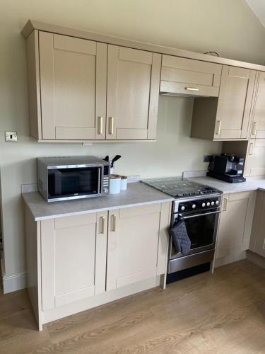 a kitchen with white cabinets and a microwave at Cosy small cottage in Wirral Merseyside with kitchen in Lower Bebington